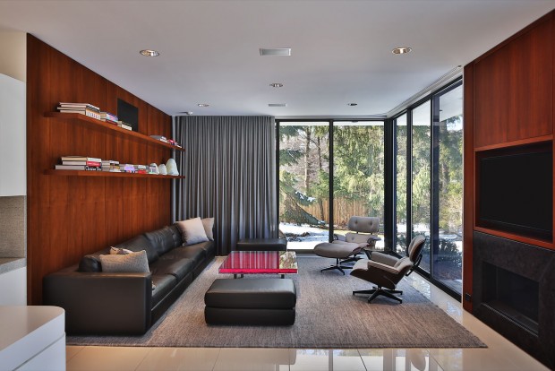 a glass enclosed living room, featuring warm wood paneling and ultra modern furniture, photographed by Jacob Rosenfeld